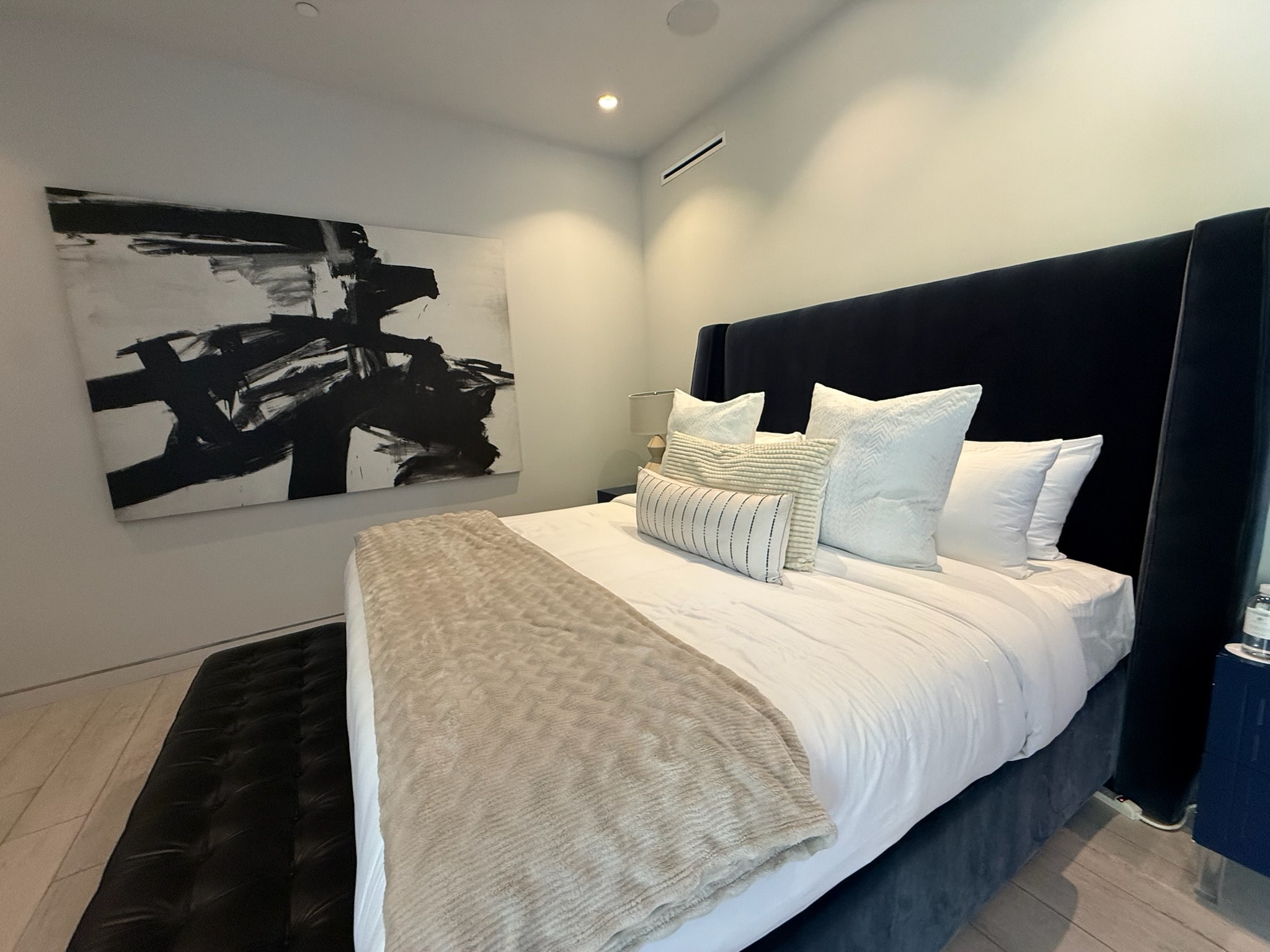 Modern bedroom with black headboard and abstract art